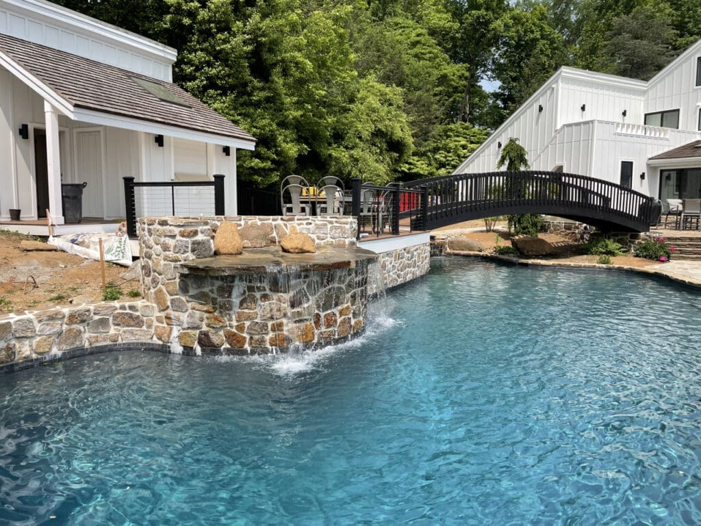 A natural stone water feature that pools under a black bridge