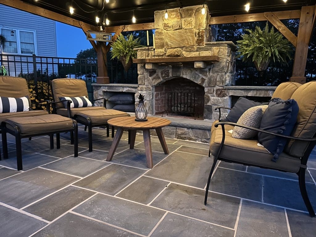 An outdoor fireplace built with furniture, lighting, and flagstone flooring